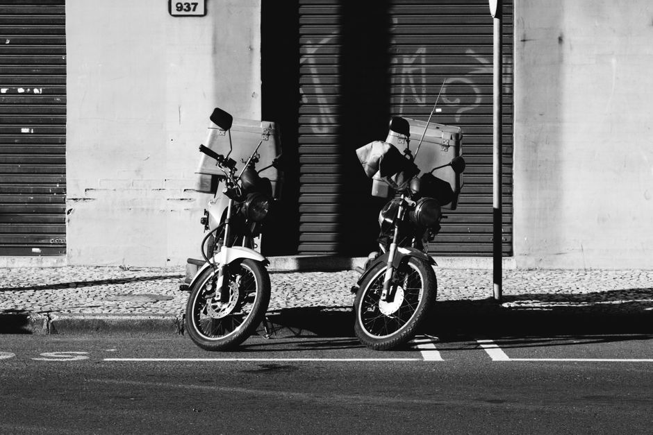 Two motorcycles parked on an urban street in black and white.